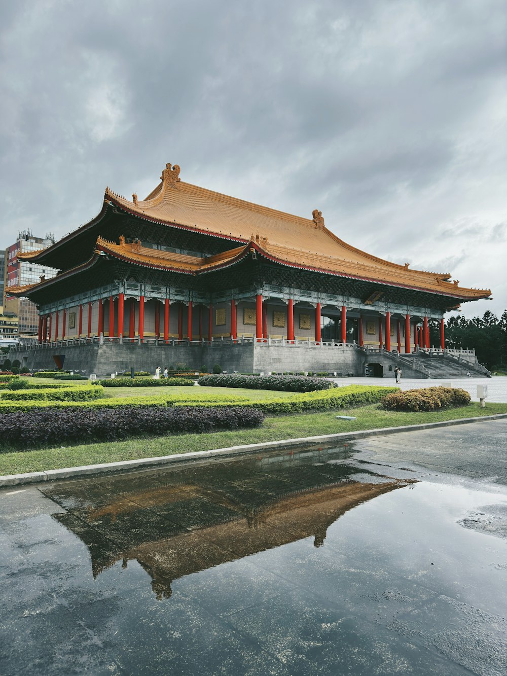 a large building with a red roof and a pond in front of it