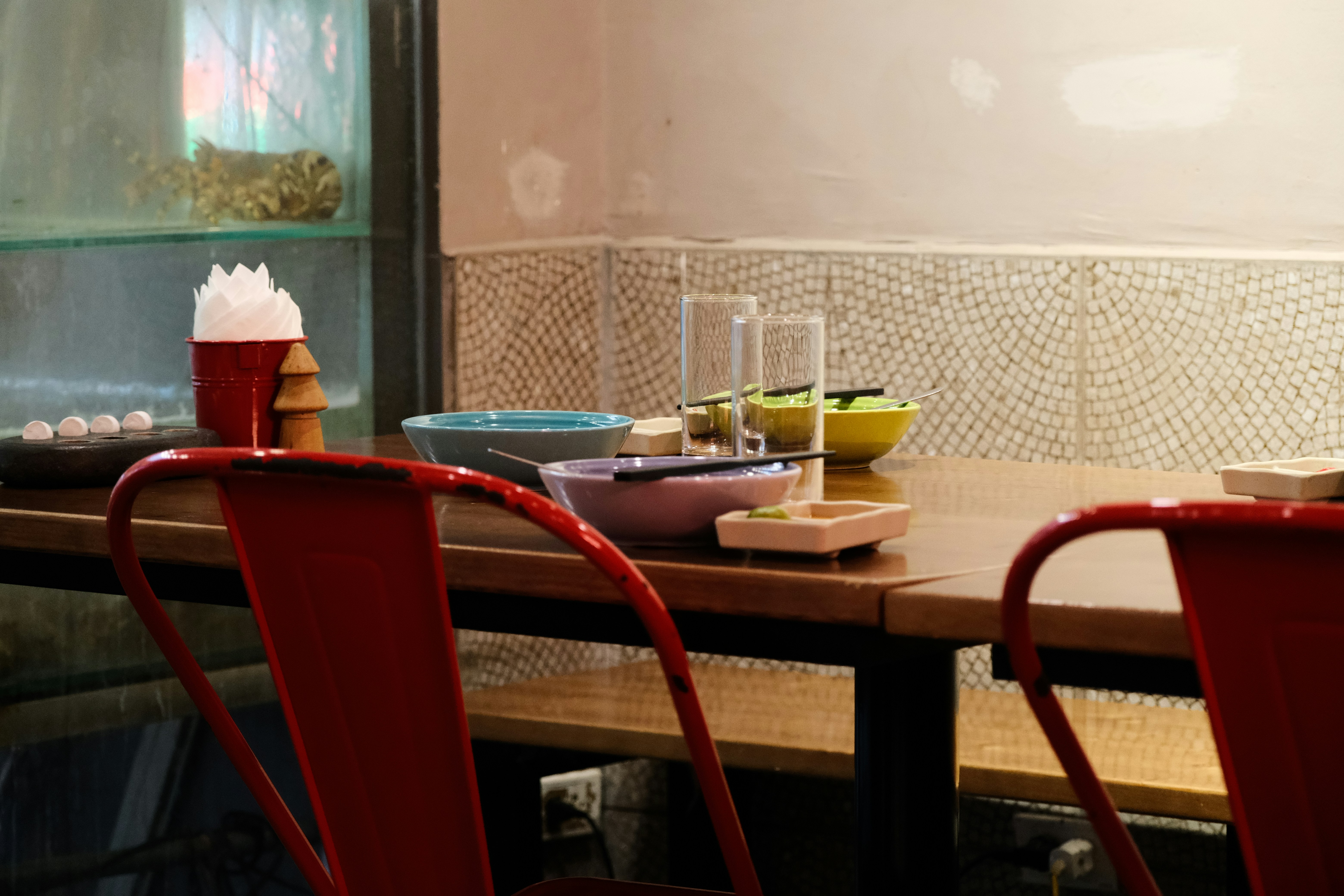 a wooden table topped with red chairs next to a bowl of food