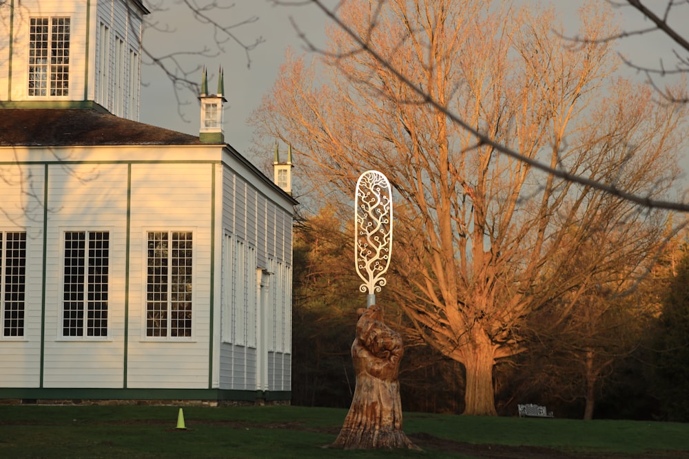 a tall white clock sitting on the side of a tree