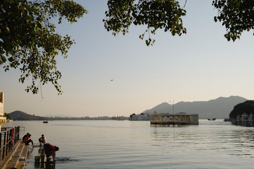 a group of people standing on a dock next to a body of water