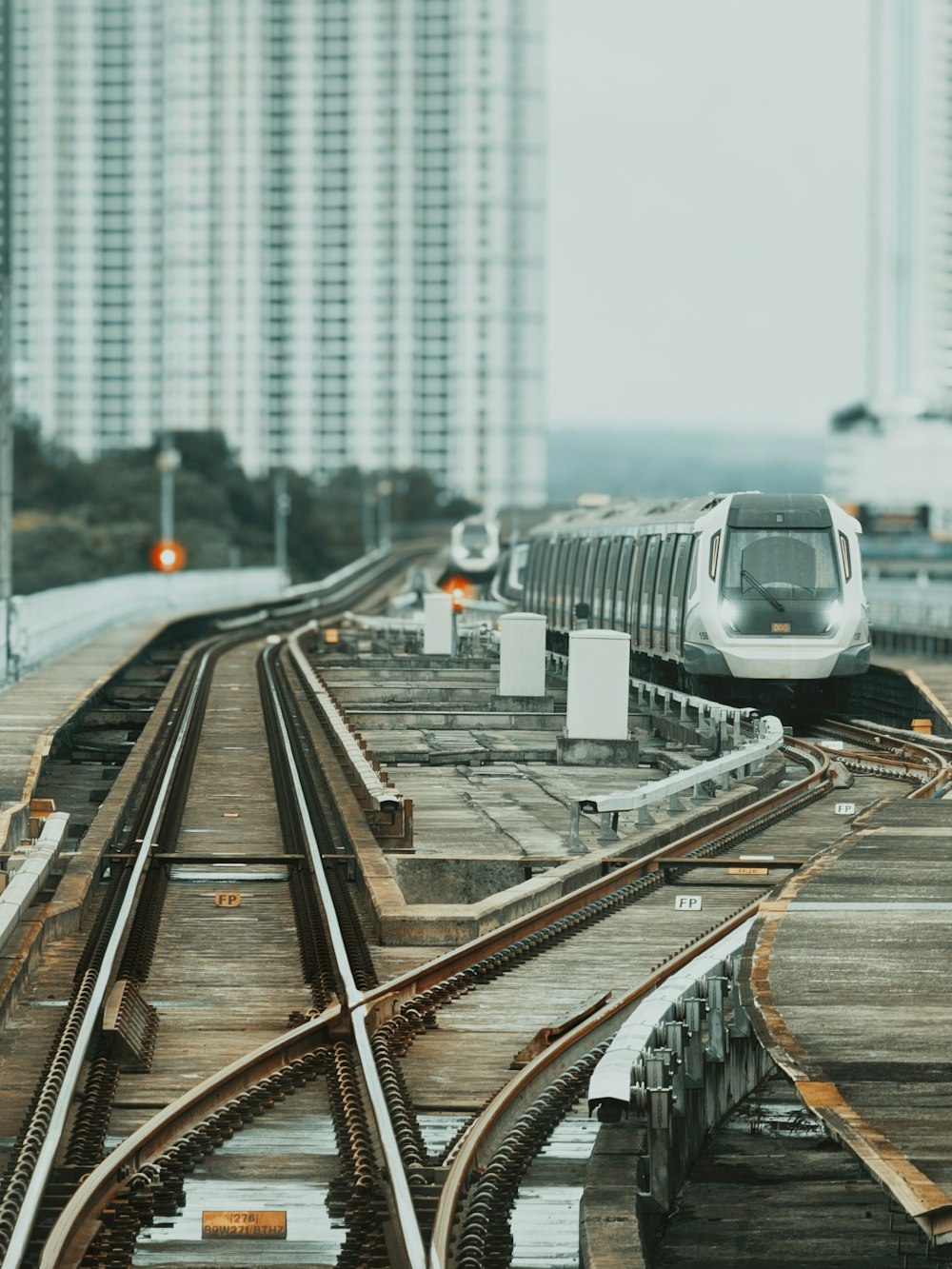 a silver train traveling down train tracks next to tall buildings