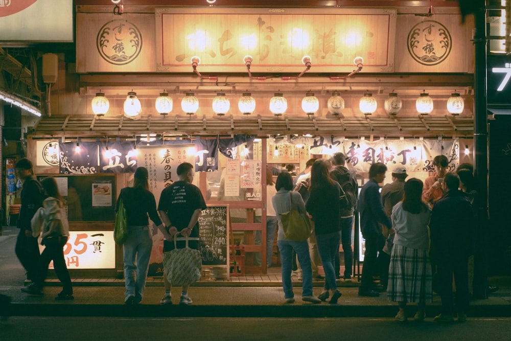 a group of people standing outside of a store at night