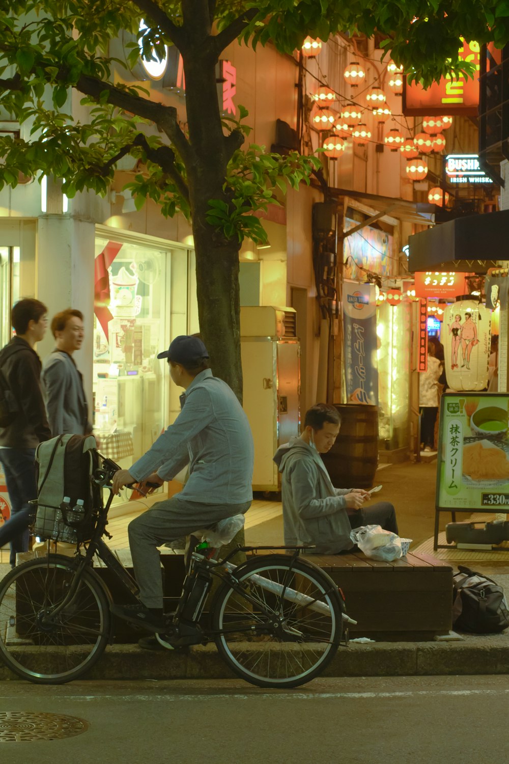 a man riding a bike down a street next to a man sitting on a bench