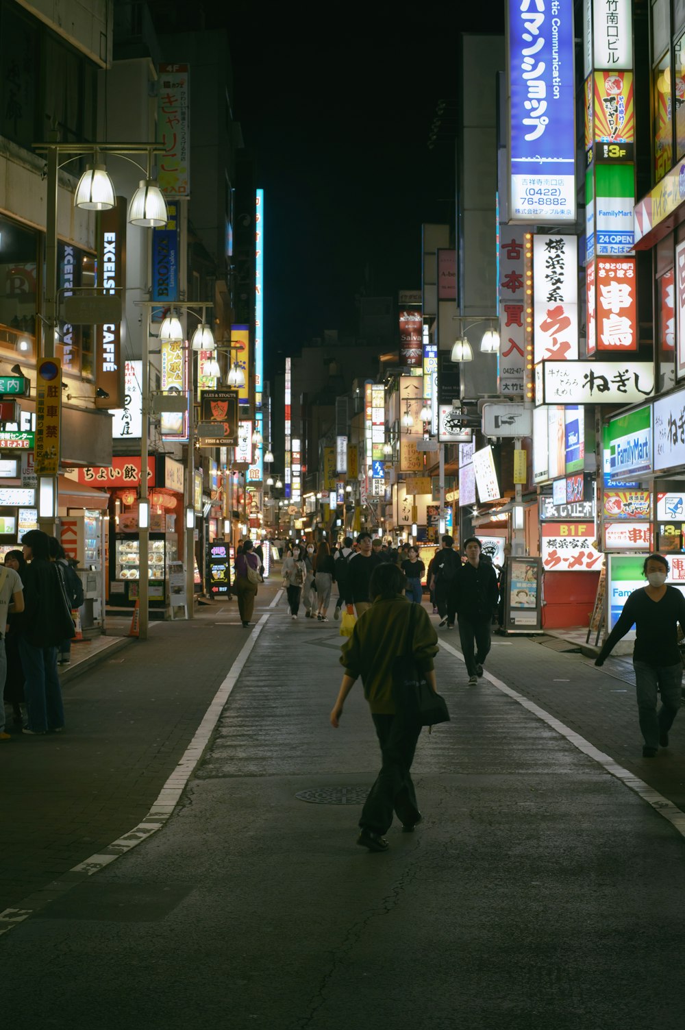 una strada affollata di città di notte con persone che camminano