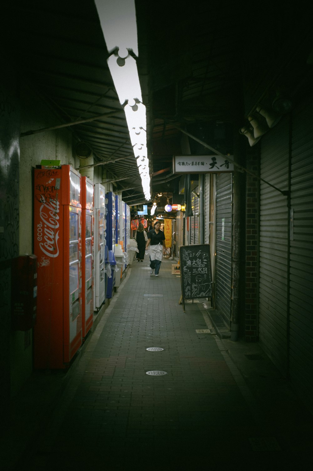 a dark alley with a few people walking down it