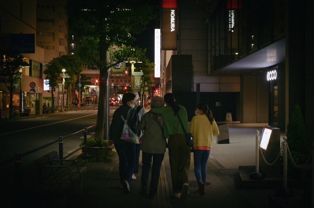 a group of people walking down a street at night