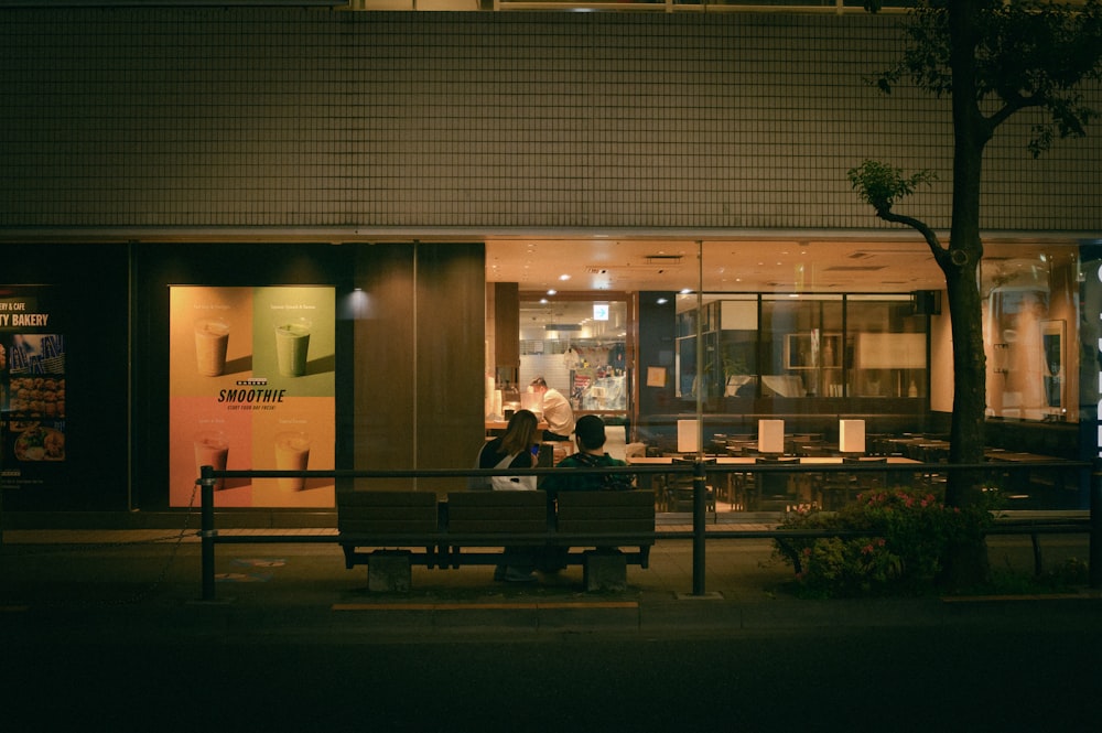 a couple of people sitting on a bench in front of a building