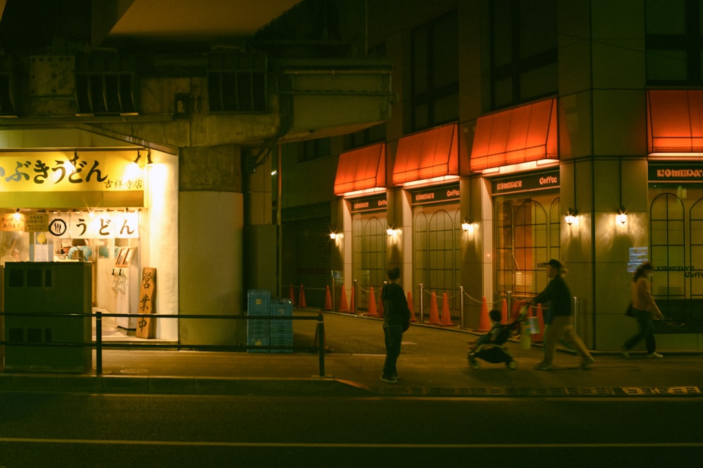 a group of people walking down a street at night