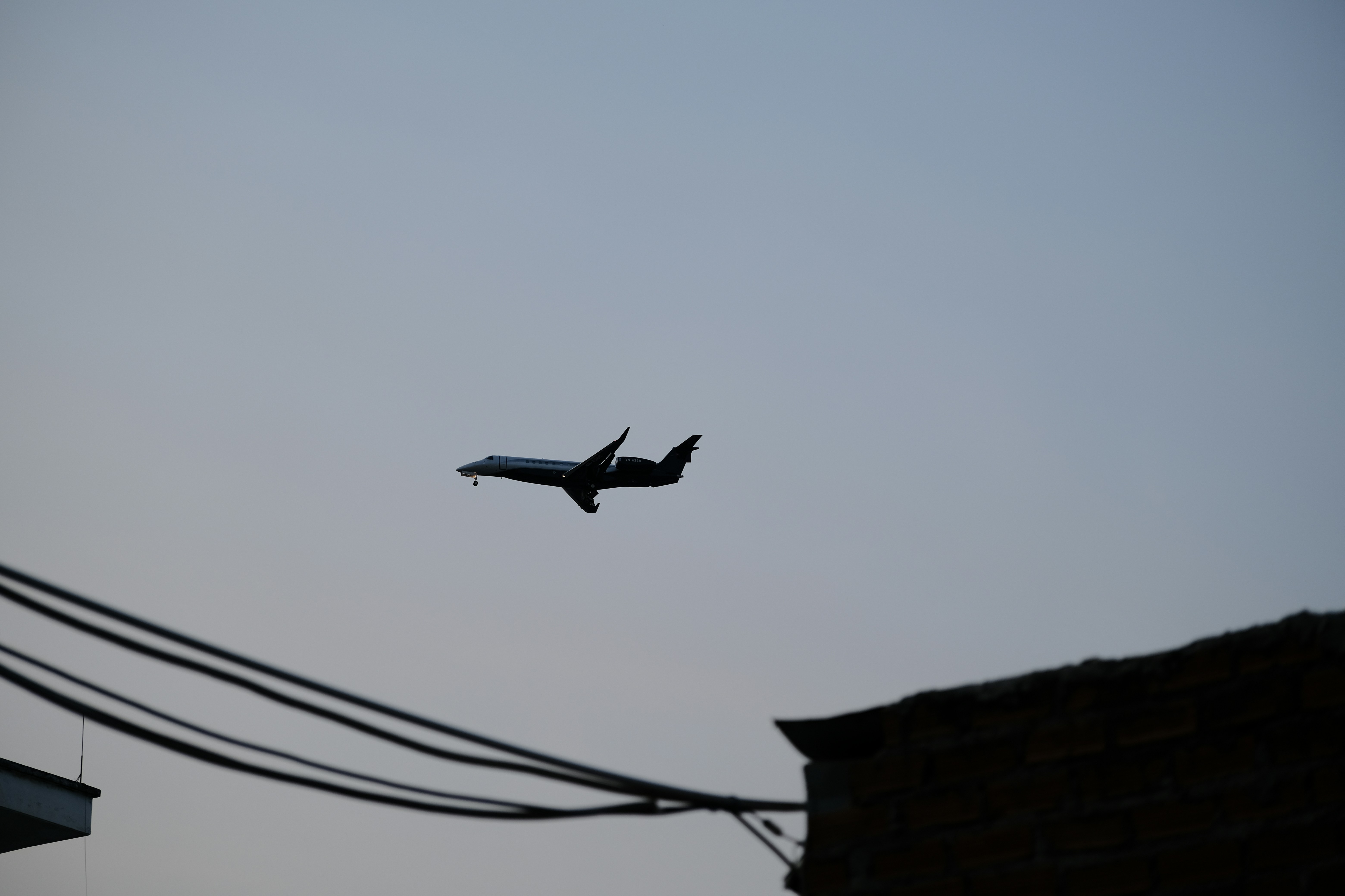 an airplane is flying over a building and power lines, 