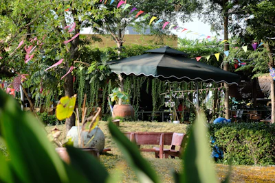 a patio with a large black umbrella and lots of plants