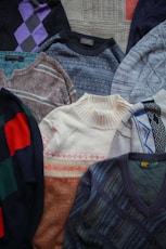 a pile of sweaters sitting on top of a bed