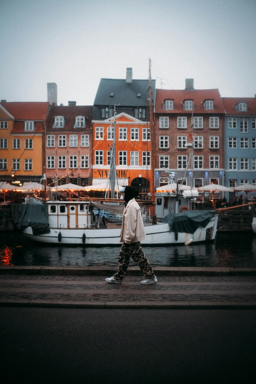 a man walking down a street next to a body of water