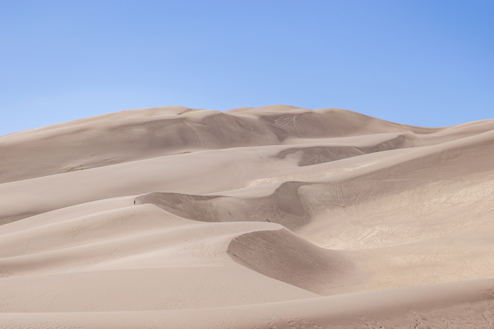 a group of sand dunes with a blue sky in the background