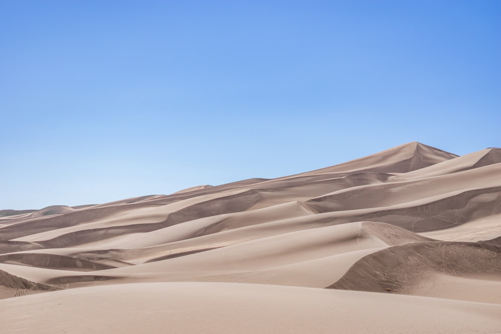 a large group of sand dunes under a blue sky