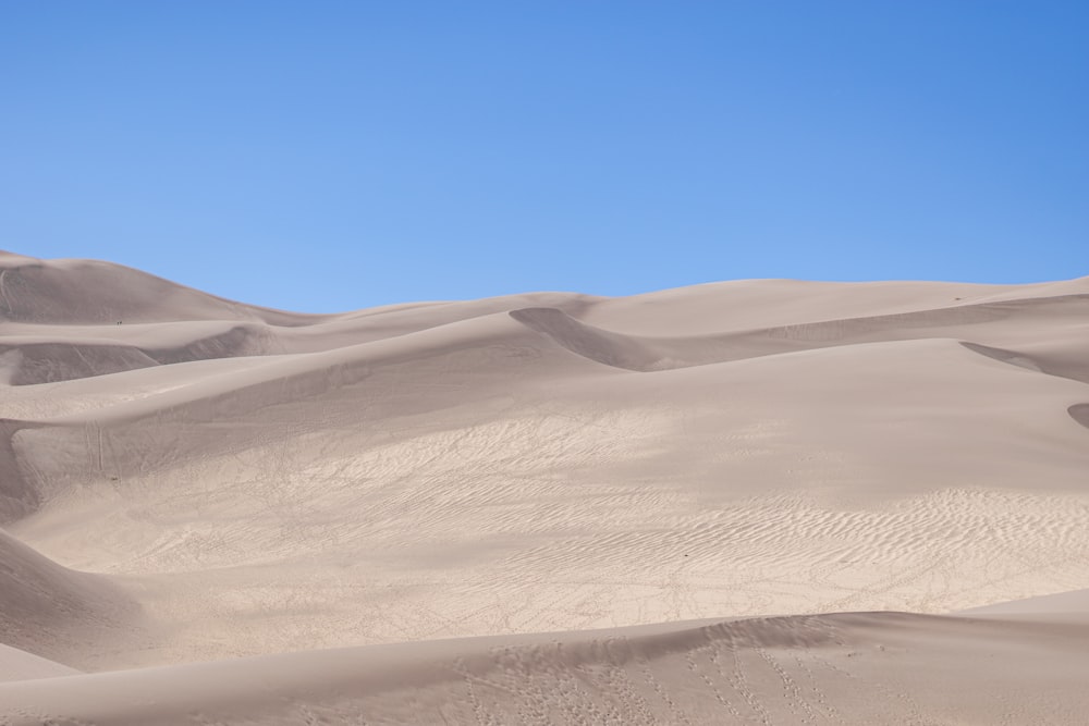 a large group of sand dunes with a blue sky in the background