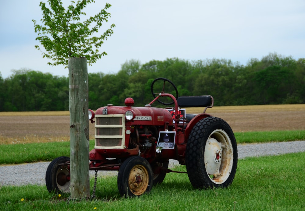 a red tractor parked next to a tree