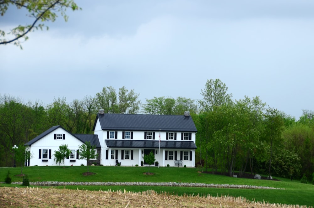 a large white house sitting on top of a lush green field