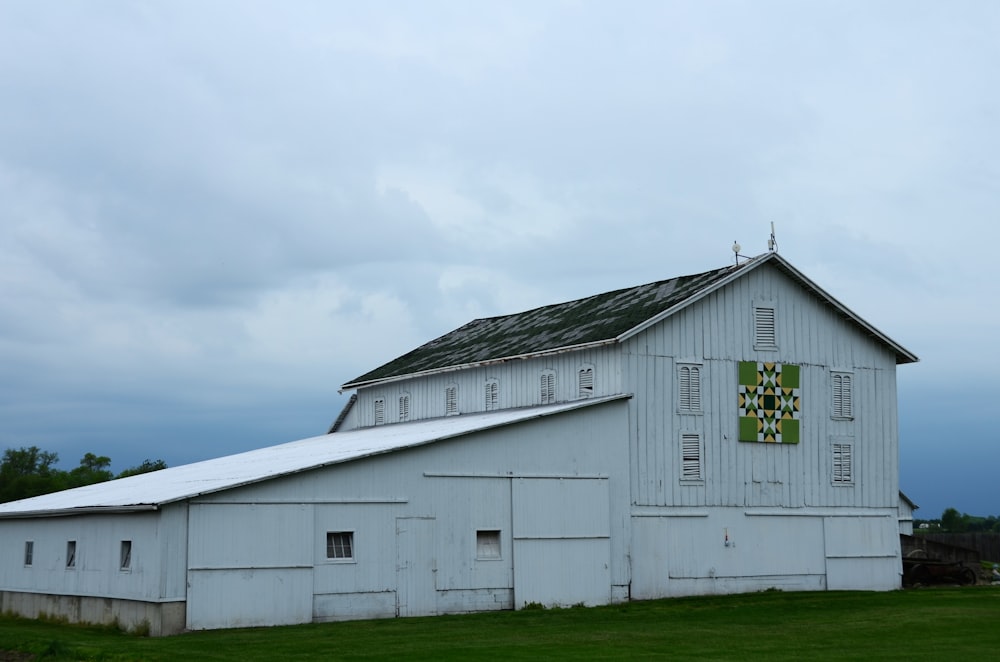 a large white barn sitting on top of a lush green field