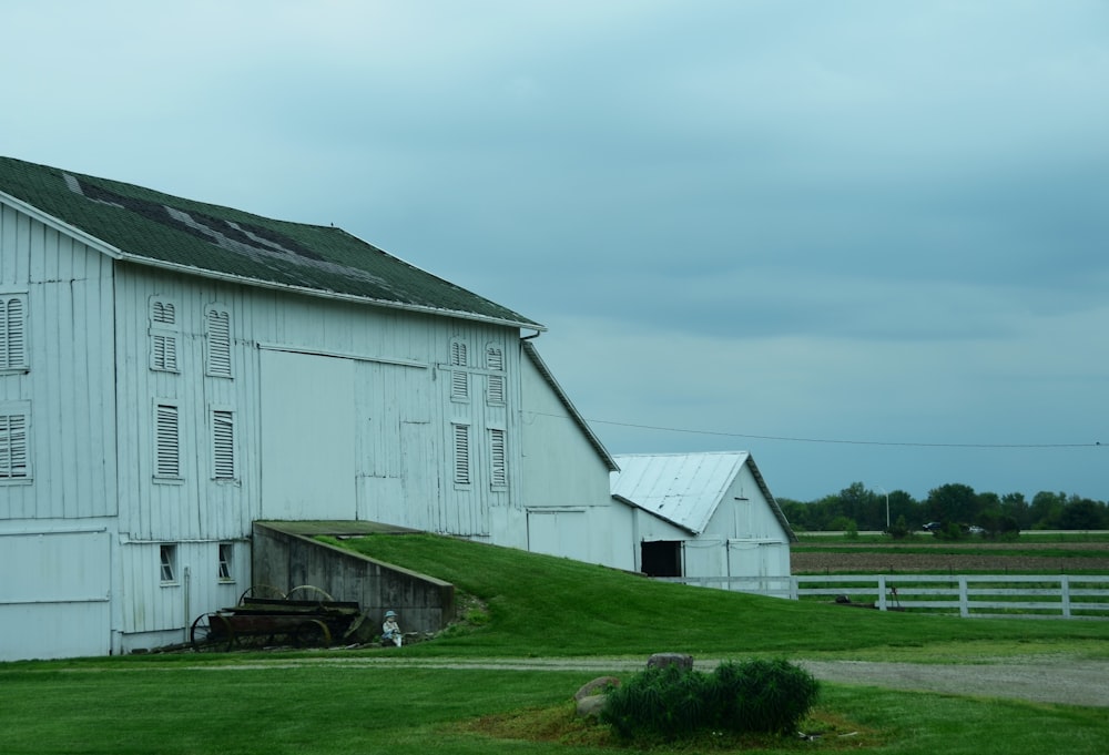 a large white barn sitting on top of a lush green field