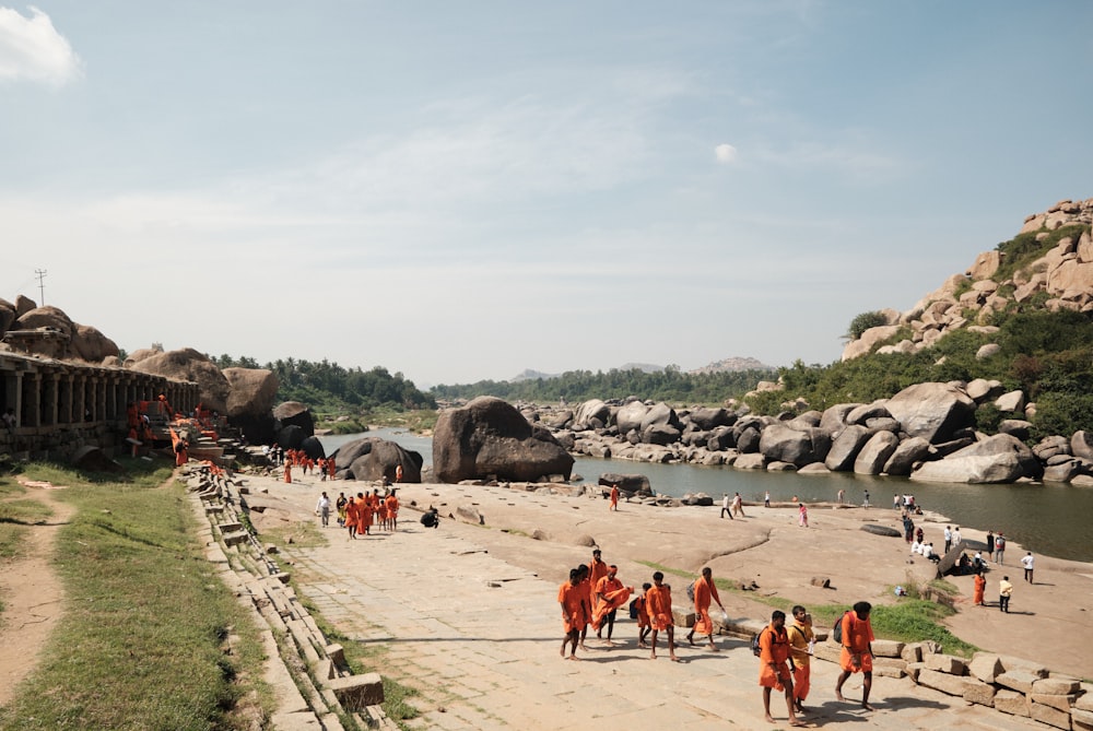 um grupo de pessoas caminhando em uma praia ao lado de um corpo d'água