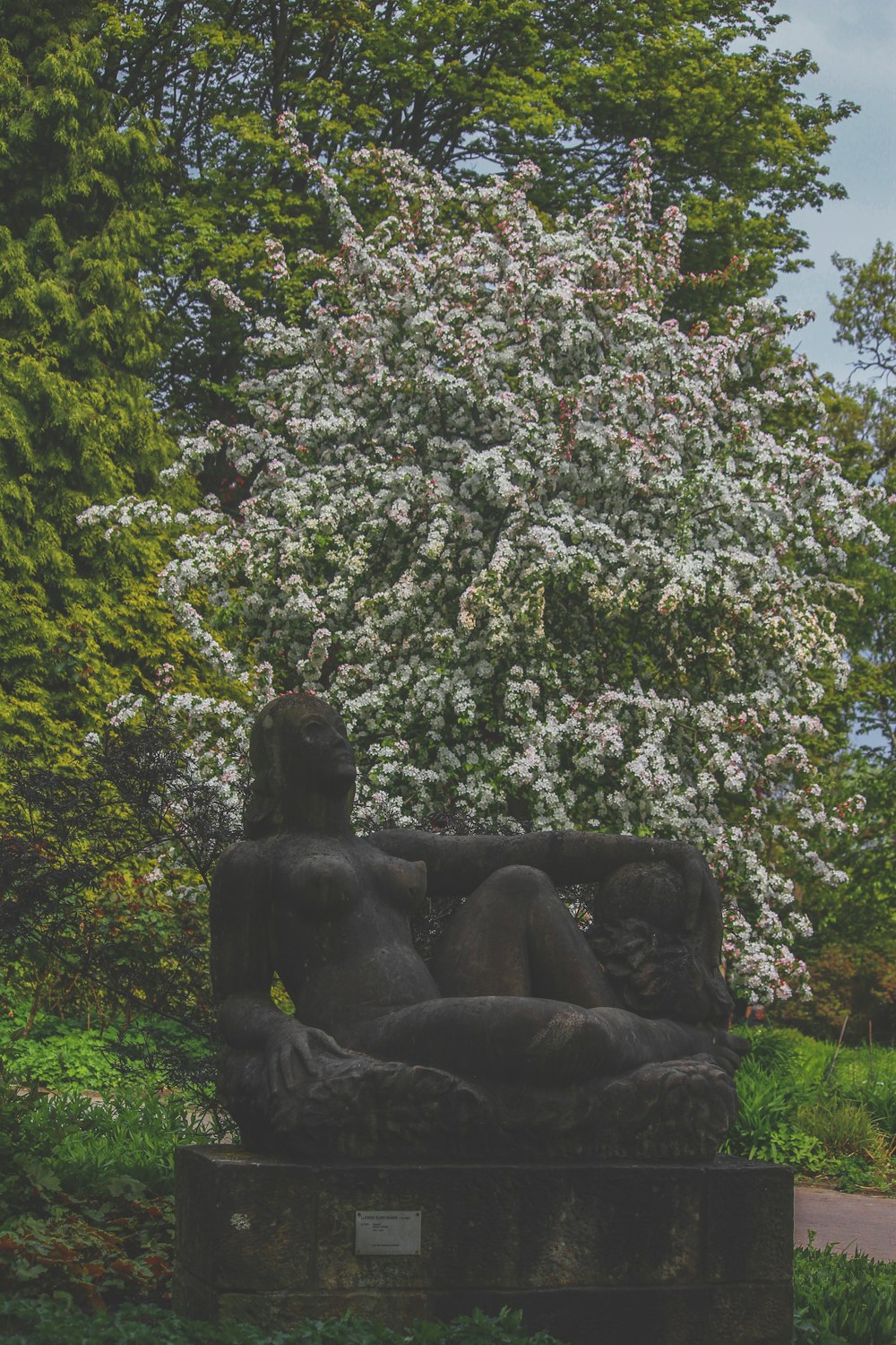 a statue in the middle of a lush green park