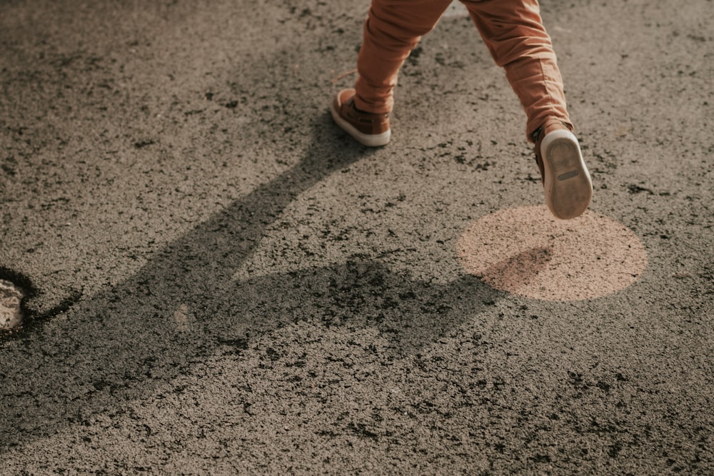 a person walking across a street next to a pot hole