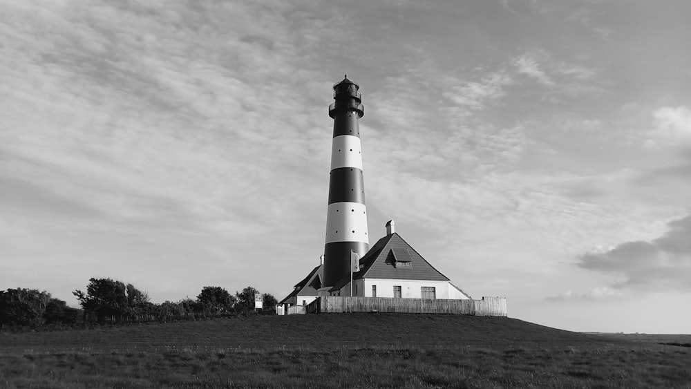 Una foto in bianco e nero di un faro su una collina