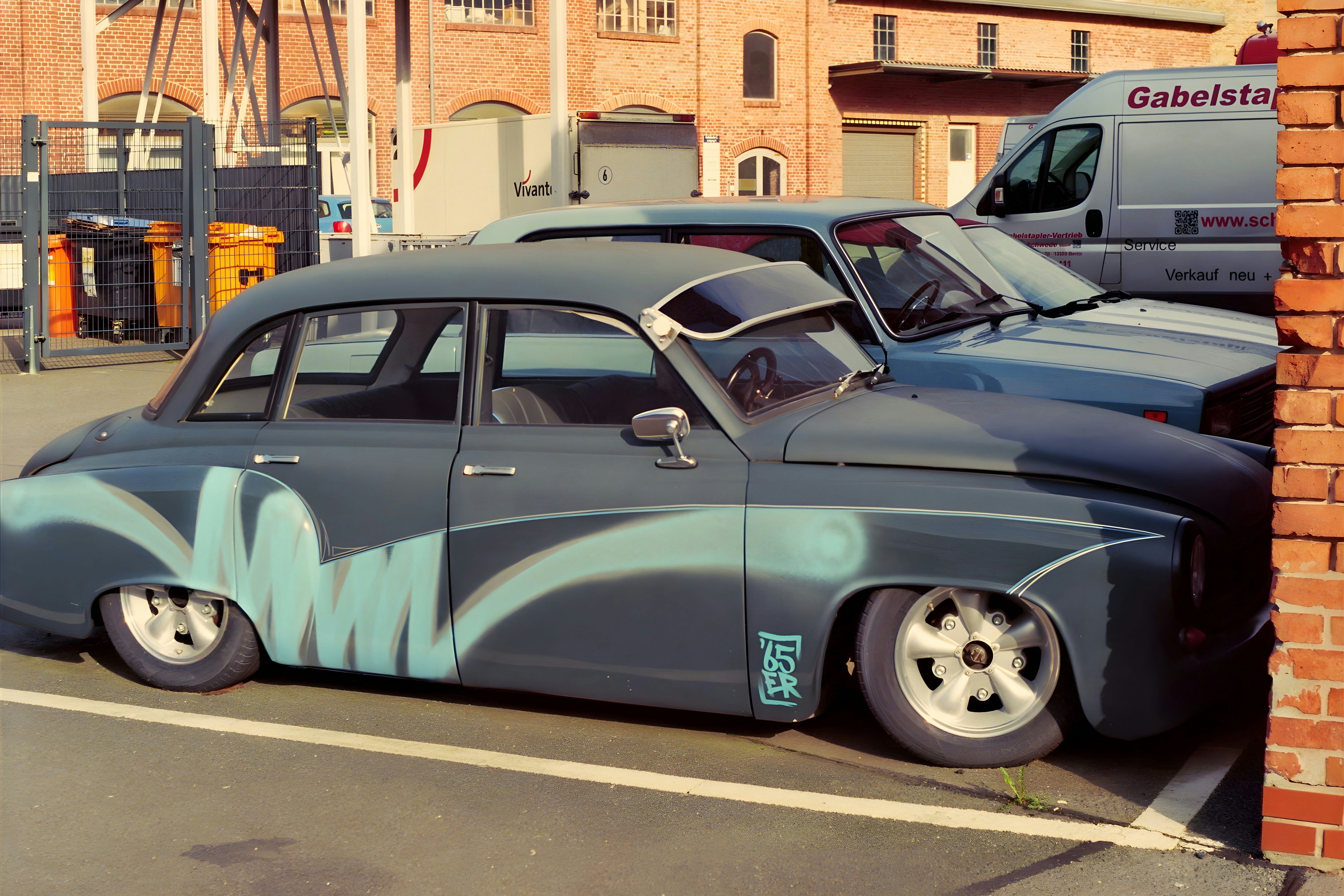 a blue car parked next to a brick building