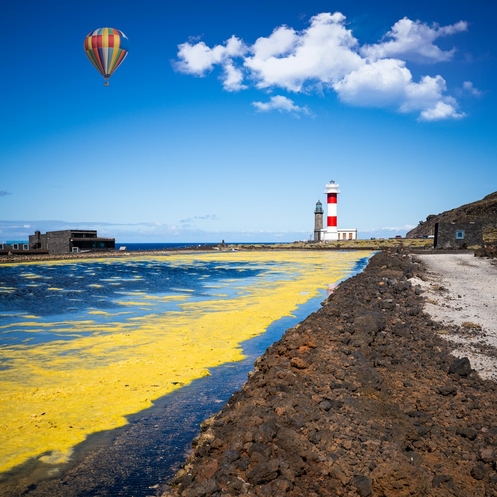 a red and white light house next to a body of water