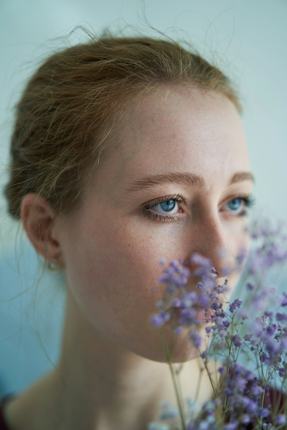 a woman with blue eyes holding a bunch of flowers