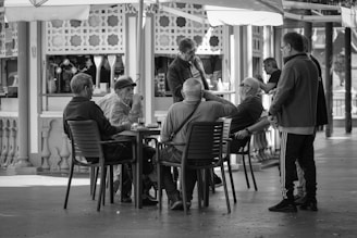 a group of men sitting at a table under an umbrella