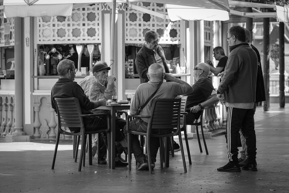 a group of men sitting at a table under an umbrella