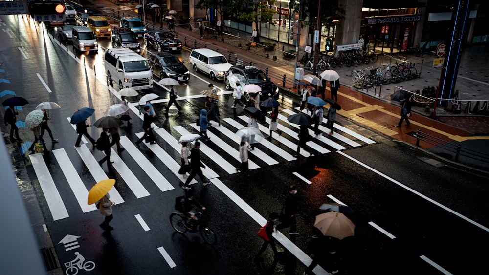 a group of people walking across a street holding umbrellas