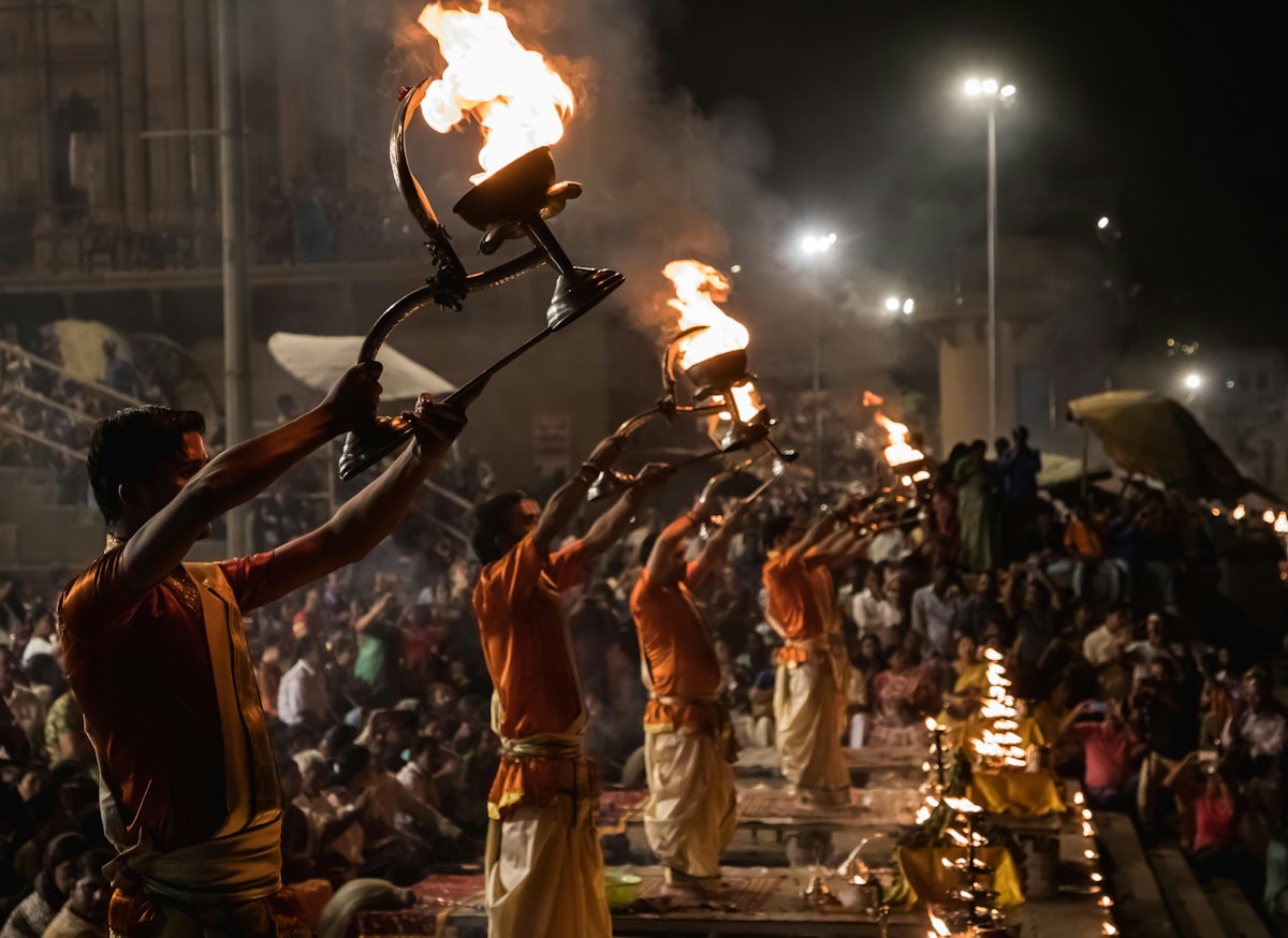 Priests holding raised flame lamps during an evening aarti ceremony on a Varanasi ghat