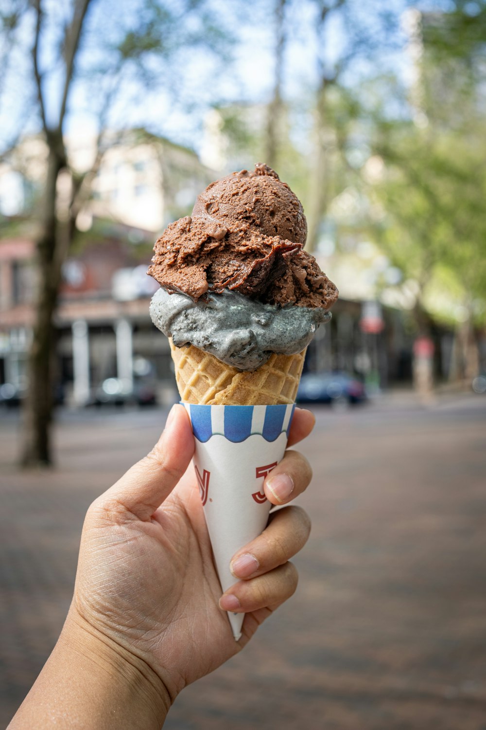 a hand holding an ice cream cone on a street