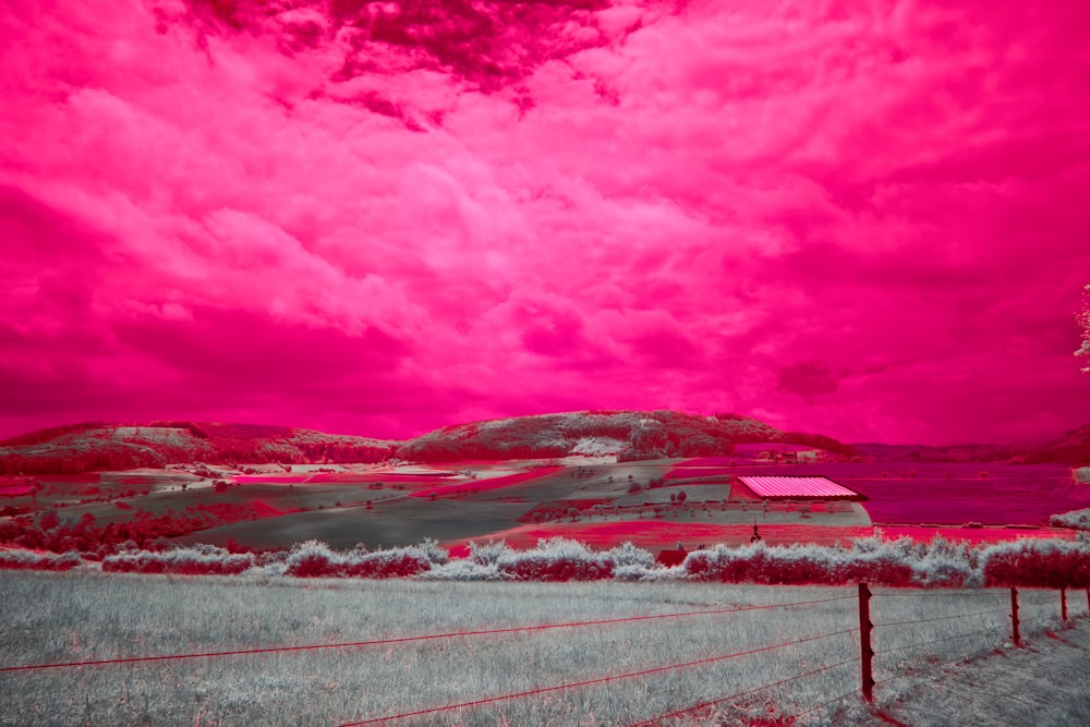 a field with a fence and a red sky