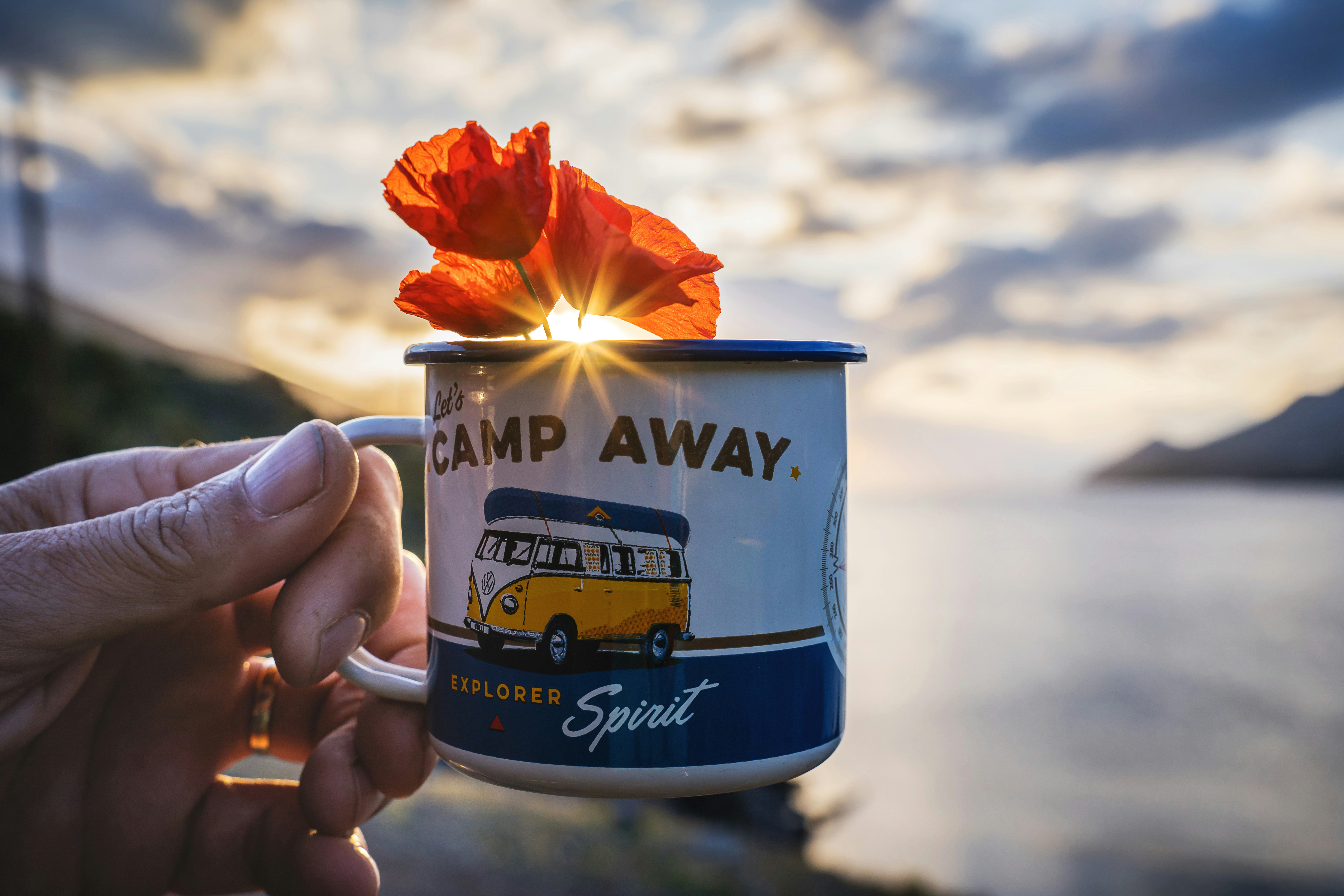 a person holding a coffee mug with a flower in it