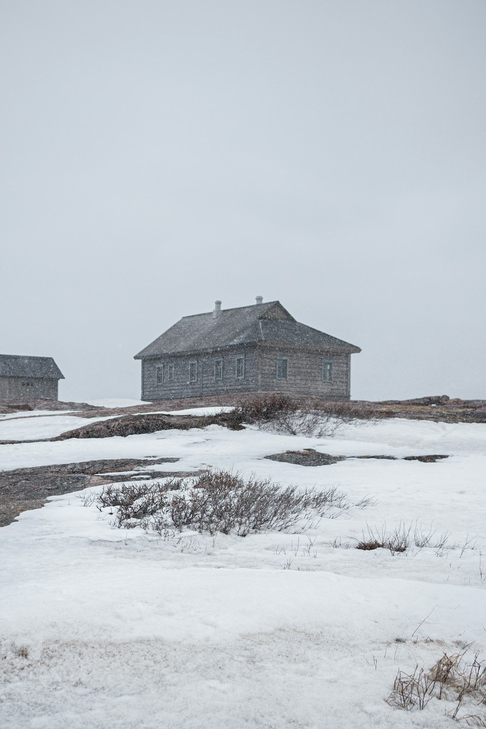 a couple of houses sitting on top of a snow covered field