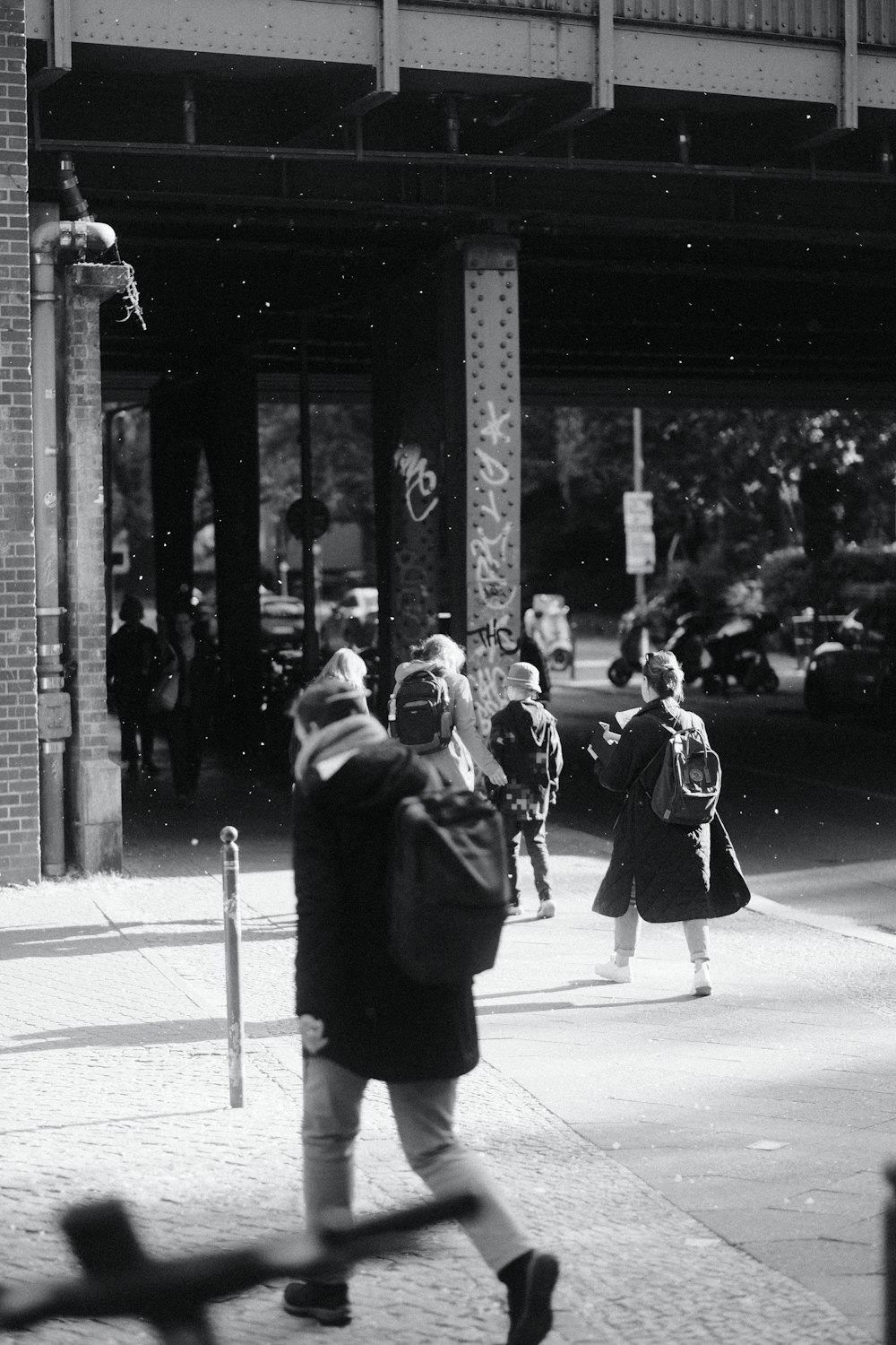 a black and white photo of people walking on a sidewalk