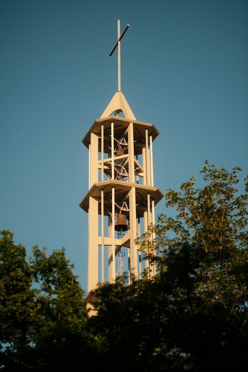 ein hoher Uhrenturm mit einem Kreuz auf der Spitze