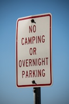 a no camping or overnight parking sign on a pole