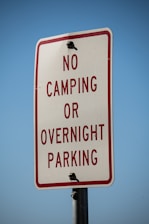 a no camping or overnight parking sign on a pole