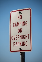 a no camping or overnight parking sign on a pole