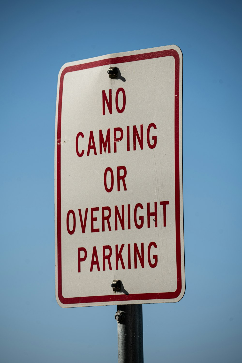 a no camping or overnight parking sign on a pole