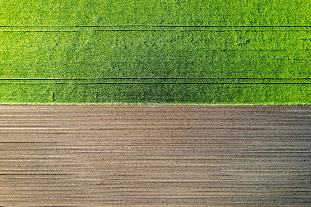 an aerial view of a green field and a brown field