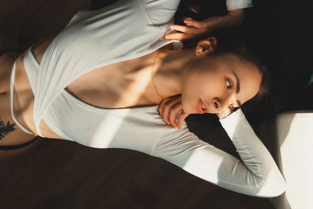 a woman in a white top is laying on the floor