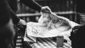 a black and white photo of a person holding a map