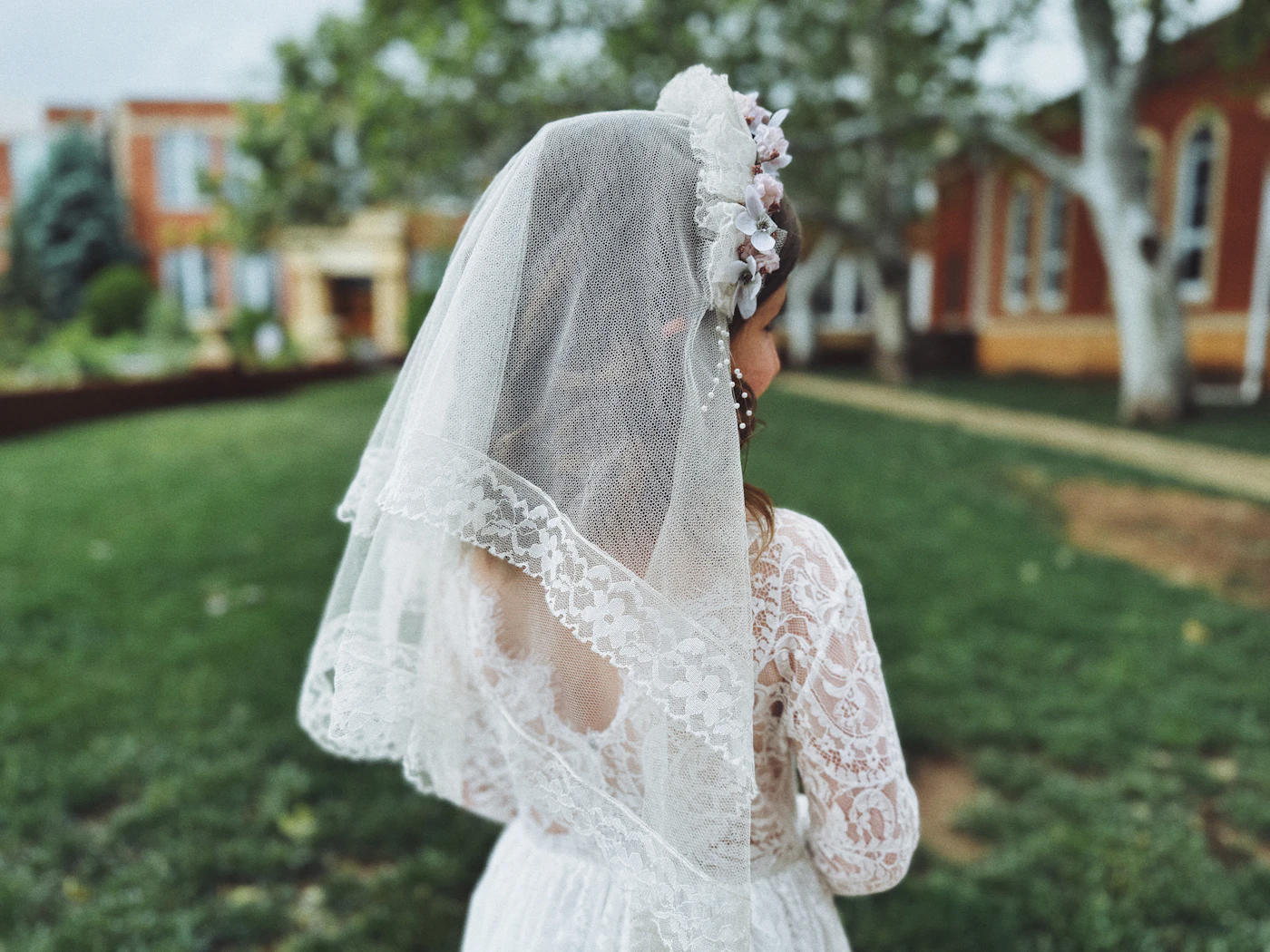 Where to rent luxury wedding dresses for one day — A bride holding a white bouquet near a floral arch.