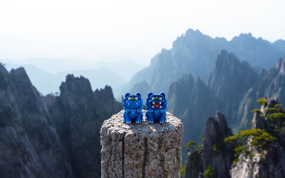 a couple of blue cats sitting on top of a wooden post