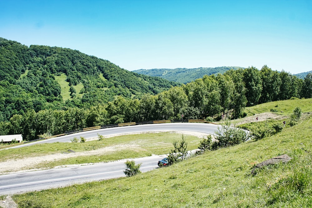 a winding road in the middle of a lush green hillside